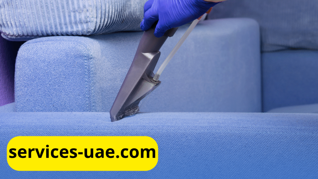عامل يستخدم جهاز بخار لتنظيف أريكة قماشية بلون أزرق داخل منزل عصري